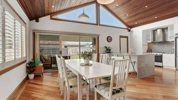 A modern kitchen with a central island, wooden flooring, and a large skylight.