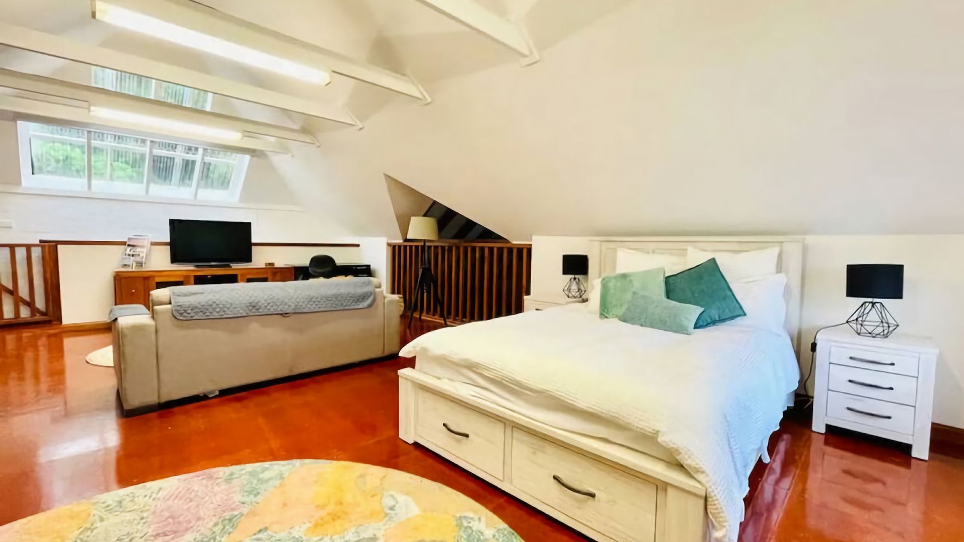 A bedroom with a bed, bedside tables, a desk, and a television.