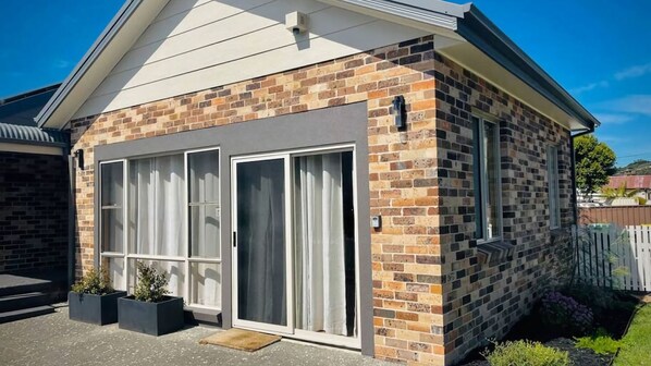 A modern house with a brick facade, large sliding glass doors, and a small porch area. - Minnamurra Retreat ~ Relaxing getaway in a serene and spacious home (Minnamurra)