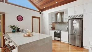Eine moderne Küche mit einer zentralen Kochinsel, Edelstahlgeräten und einer Holzbalkendecke.