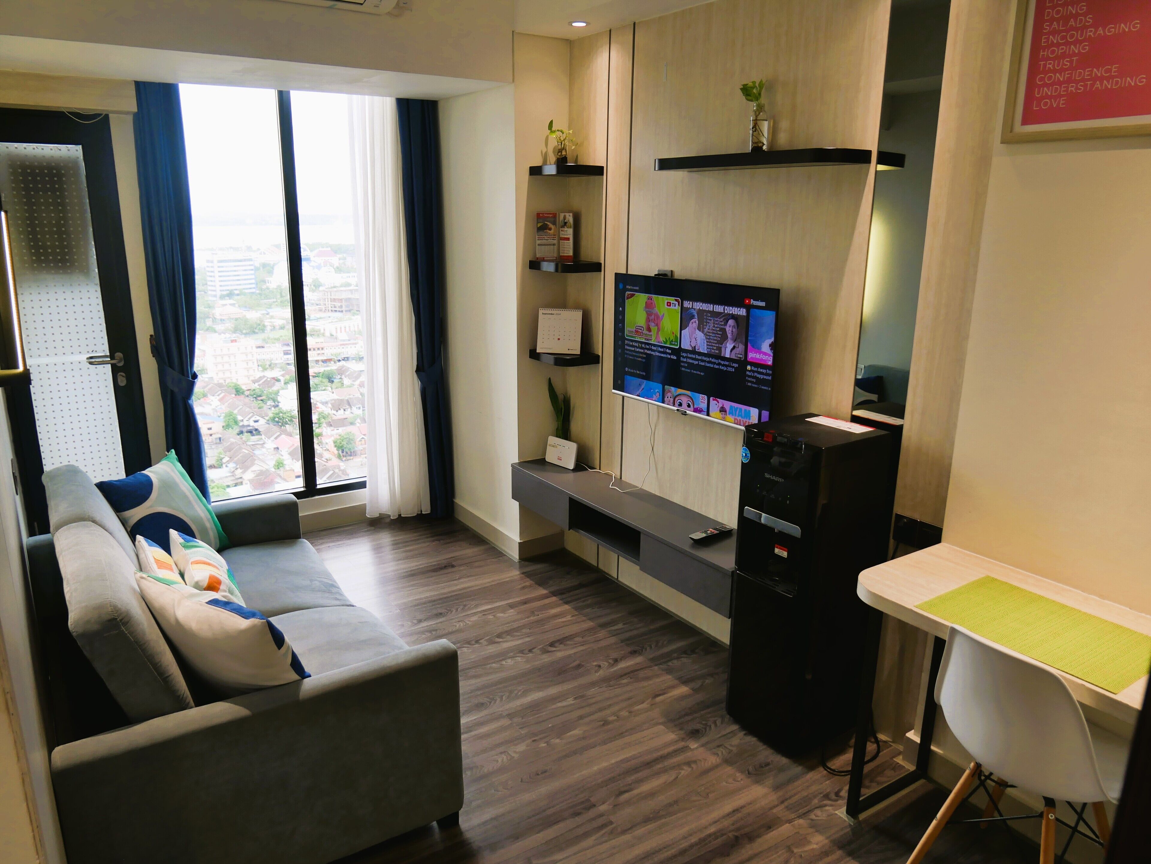 A modern living room with a sofa, a TV mounted on the wall, and a small table.