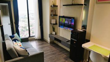 A modern living room with a sofa, a TV mounted on the wall, and a small table.