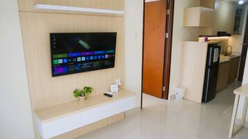 A modern living room with a flat-screen TV mounted on a wooden wall, a small plant, and a remote control on a wooden console.