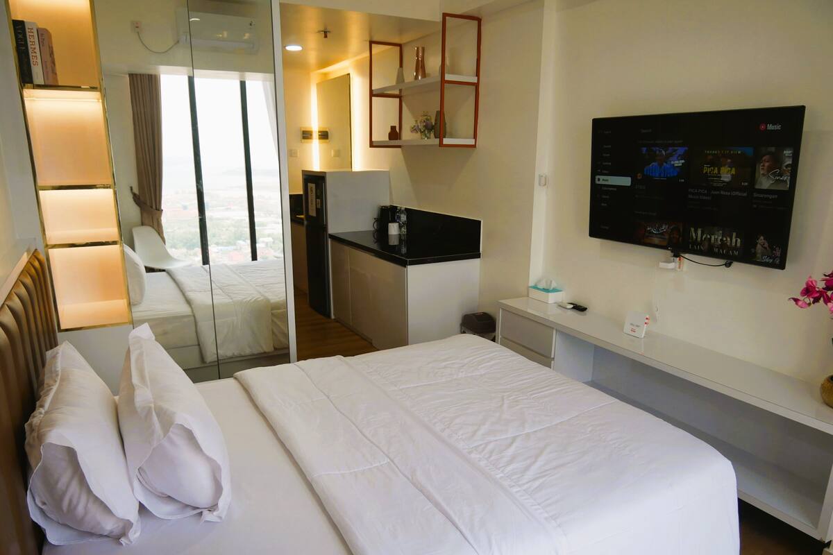 Une chambre d’hôtel avec un grand lit, un bureau, une télévision et une vue sur la ville.