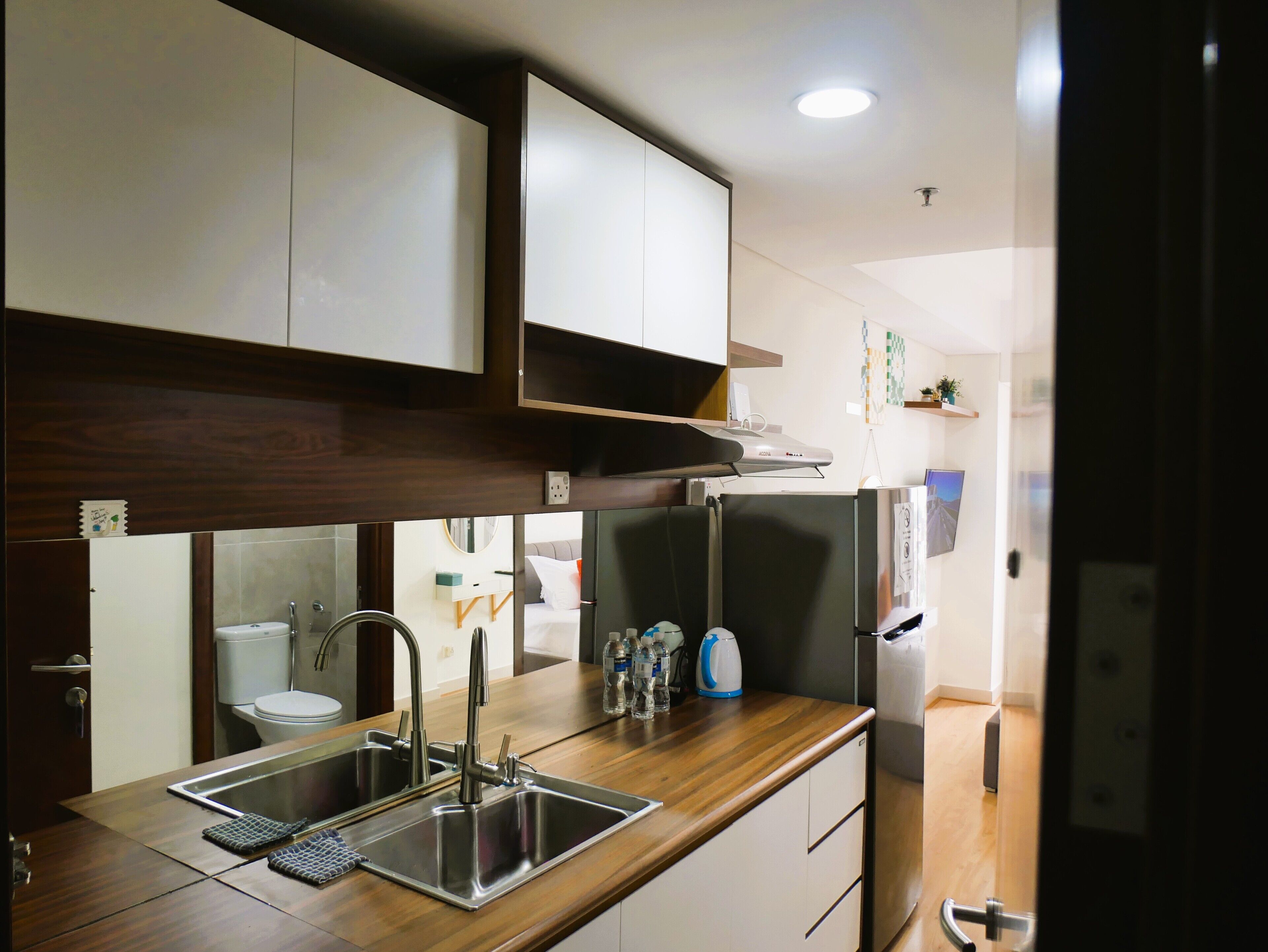 Una cocina moderna con un lavamanos de acero inoxidable, encimera de madera y armarios blancos.