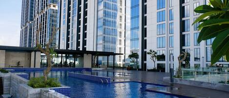 A modern building with a swimming pool, large windows, and a covered area.