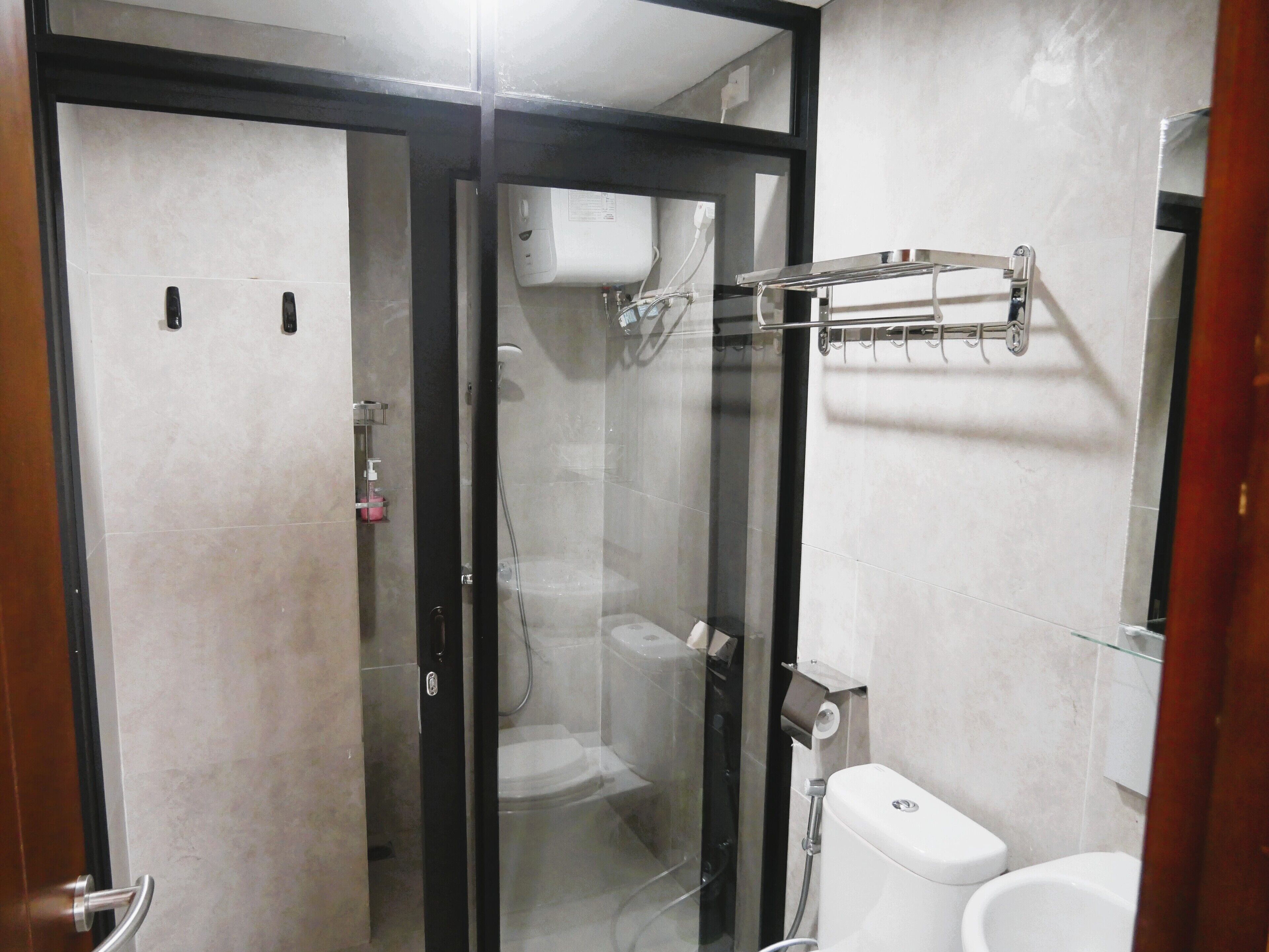 A bathroom with a glass-enclosed shower, a toilet, and a towel rack.