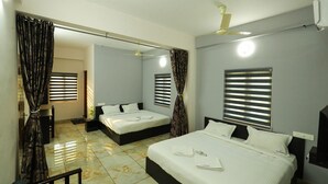 A hotel room with two beds, a ceiling fan, a large mirror, and a window with blinds. - Aldora Airport Residency (Aluva)