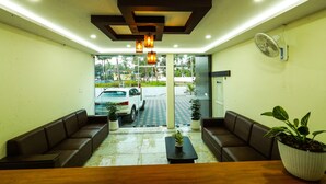 A reception area with a reception desk, seating, potted plants, and a view of the outside. - Aldora Airport Residency (Aluva)