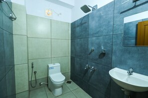 A bathroom with a toilet, shower, and sink.