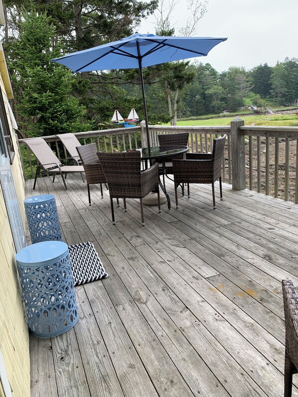 Relax on the deck with a view of the surrounding grassy area and trees.