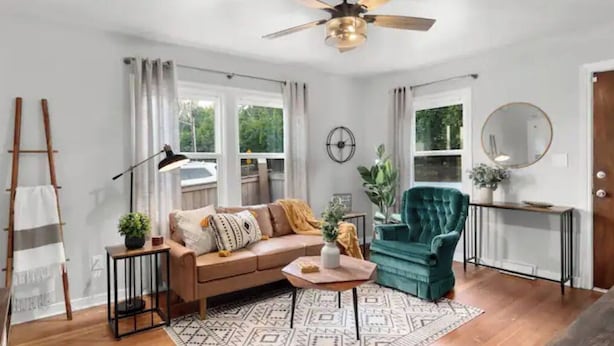 Un salon comprenant un canapé, un fauteuil, une table basse et un tapis à motifs.