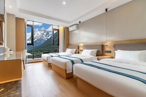 A hotel room with three beds, a desk, and a large window with a mountain view. - Shanxia Hotel (Bome)