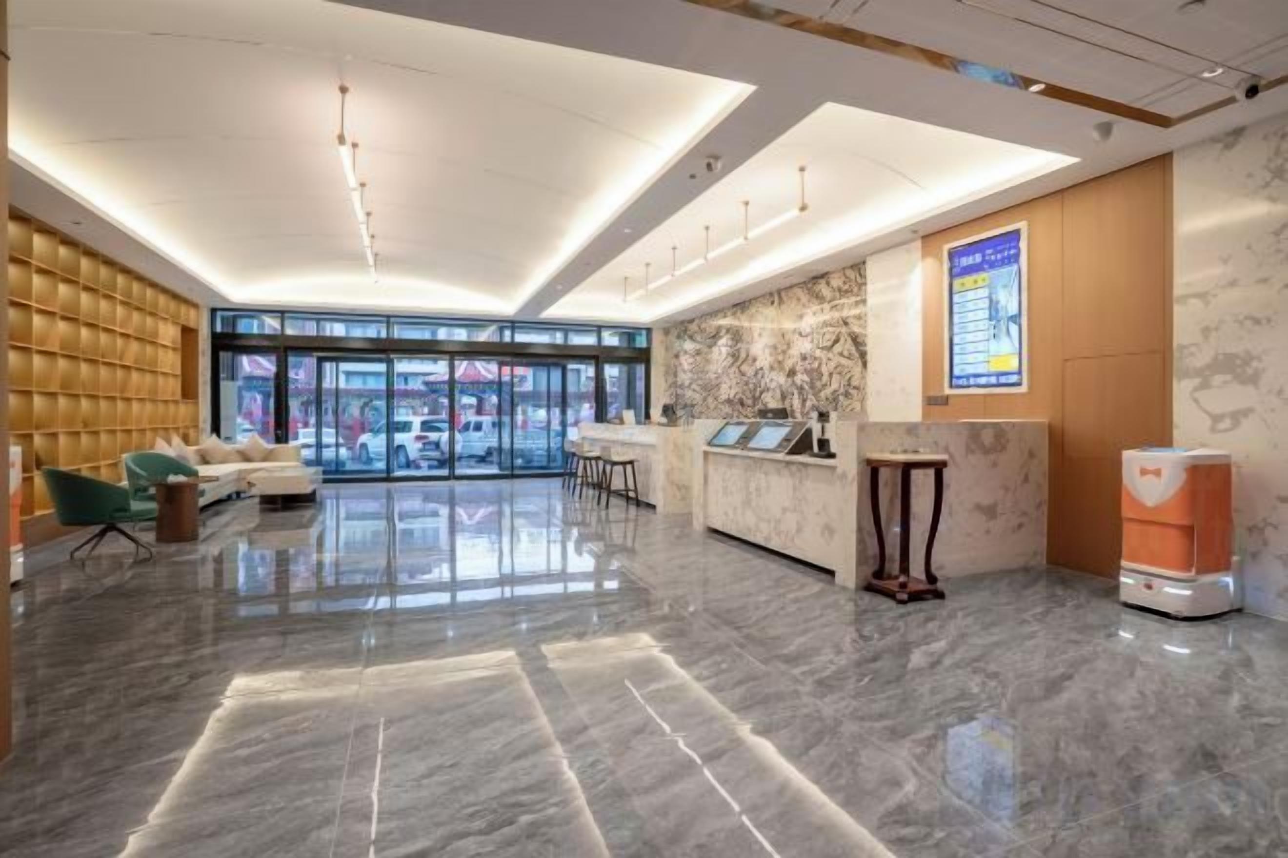 A modern hotel lobby with a reception desk, seating area, and large windows.