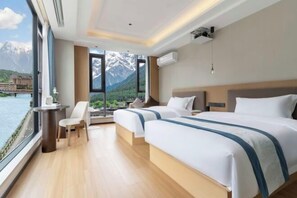 A hotel room with two beds, a view of mountains, a dining area with a table and chairs, and a large window. - Shanxia Hotel (Bome)
