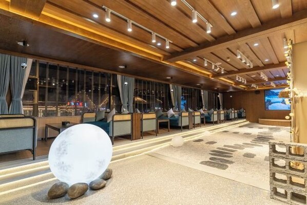 A hotel lobby with a seating area, a large spherical decorative piece, and a screen displaying a snowy landscape. - Shanxia Hotel (Bome)