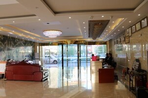 Un vestíbulo de hotel con mostrador de recepción, un sofá rojo y un candelabro.