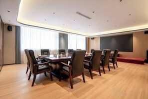 Un salón de conferencias con una larga mesa, sillas, una pantalla de proyector y una alfombra roja.