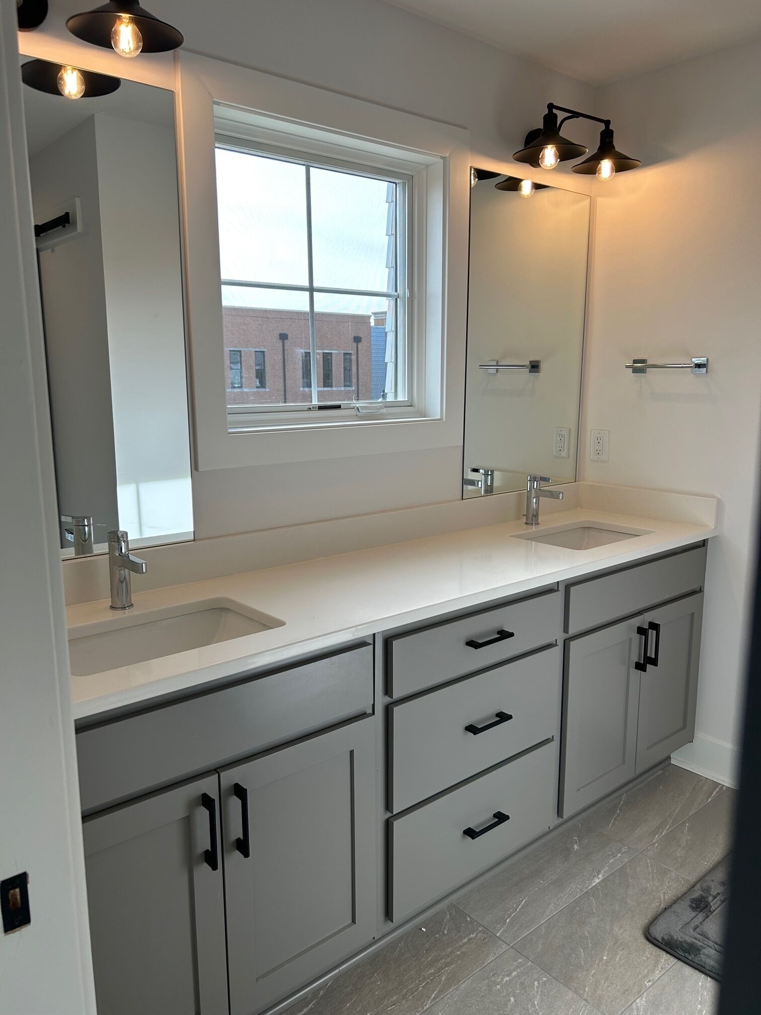Un bagno moderno con due lavabi, un grande specchio e una finestra.