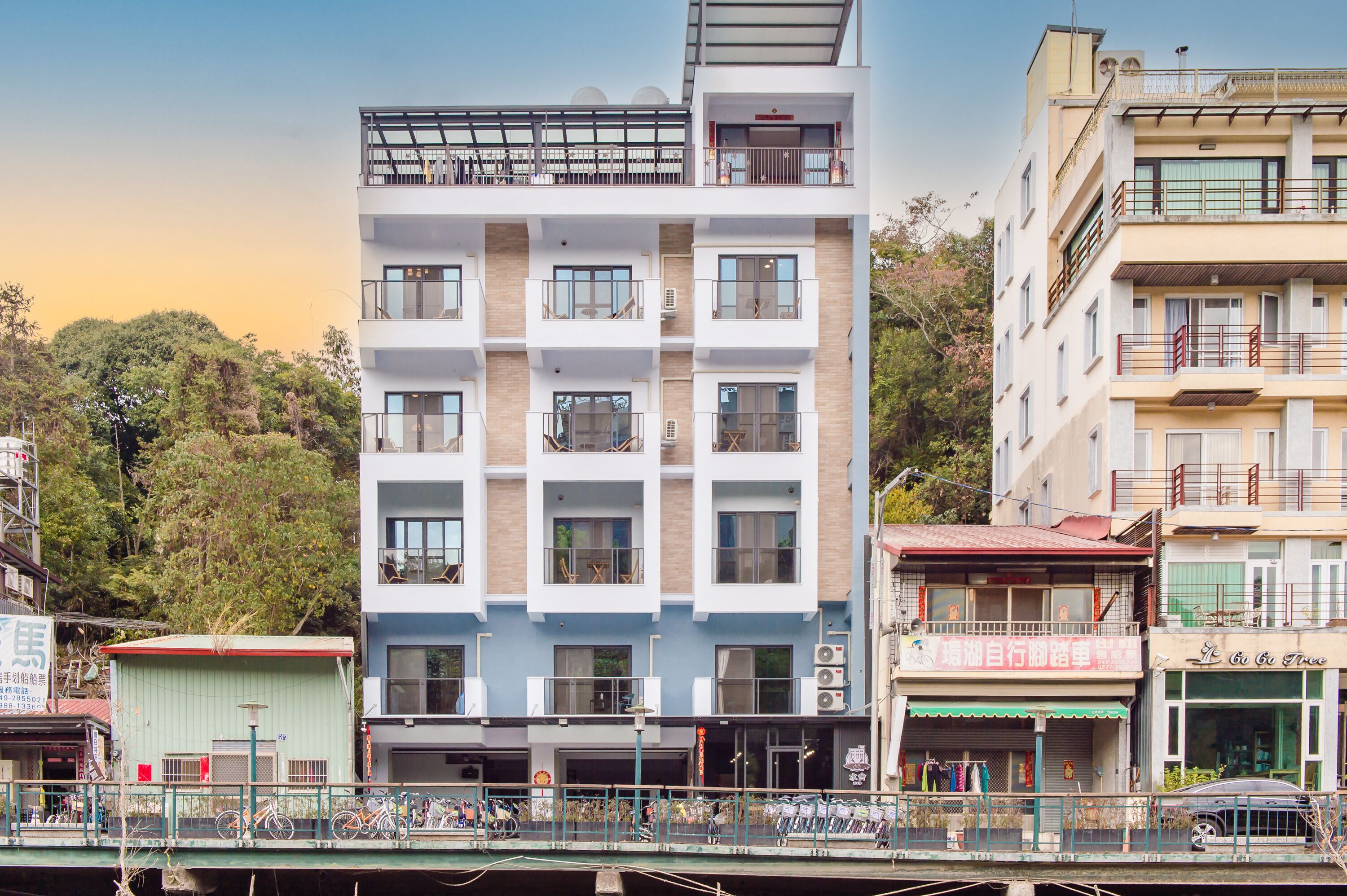 A multi-story building with balconies, a ground-level shop, and a bicycle parking area.