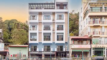 A multi-story building with balconies, a ground-level shop, and a bicycle parking area.