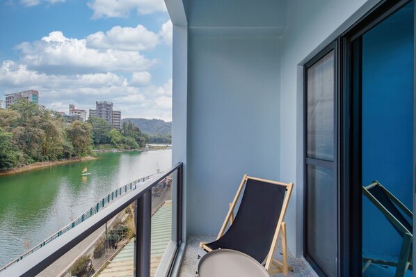 A balcony with a view of a river, a chair, and a window. - Water House (Yuchi)