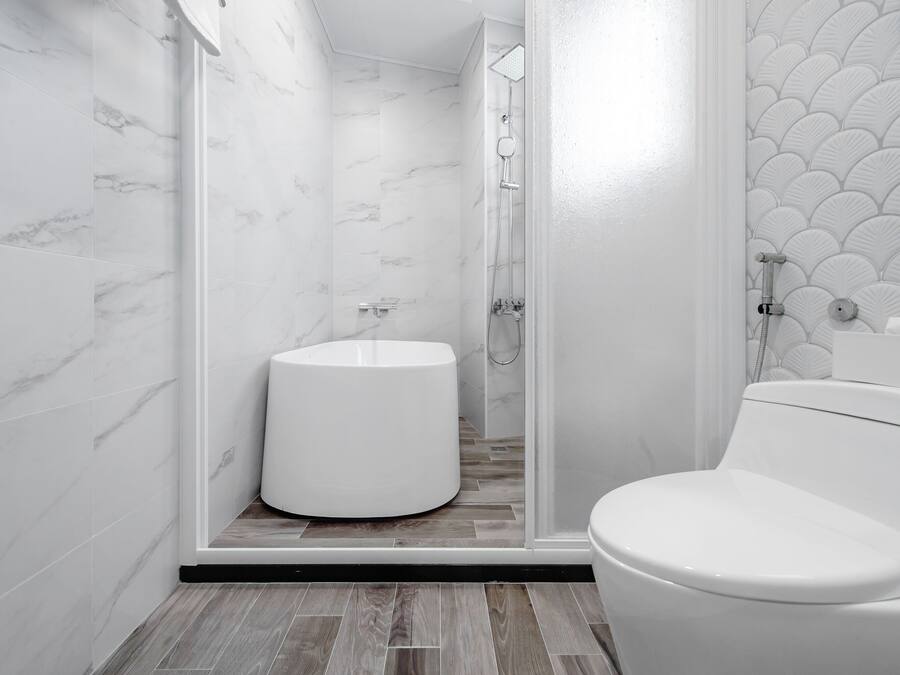 Un bagno moderno con il water, una doccia con porta in vetro e un lavandino.