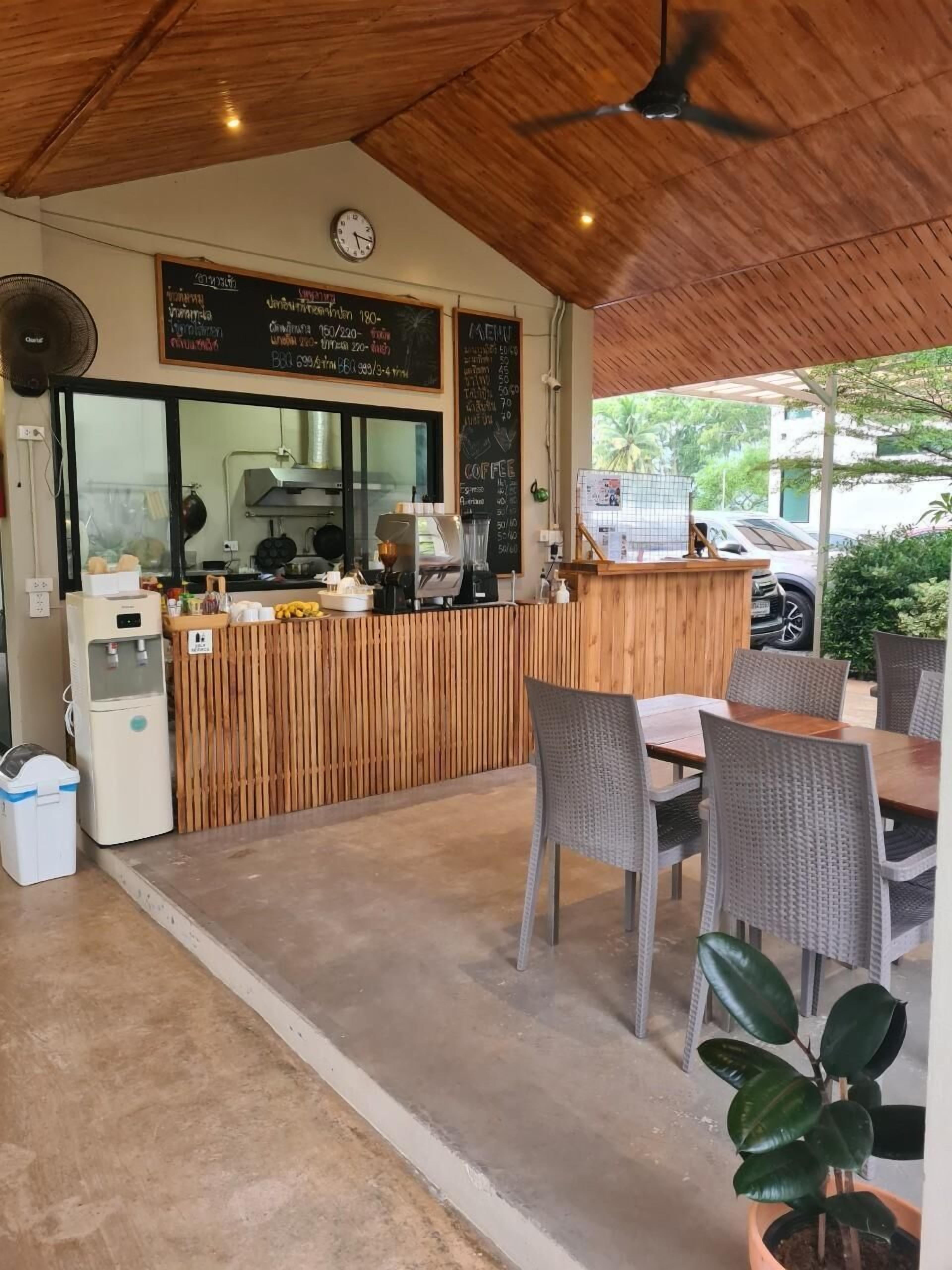 Un cafè amb un mostrador de fusta, un panell amb el menú i una zona de seients amb cadires i taula.