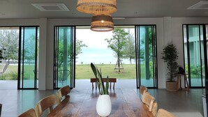 Un vaste espace dédié à la salle à manger, avec une grande table en bois, entourée de chaises, et un luminaire suspendu en rotin.
