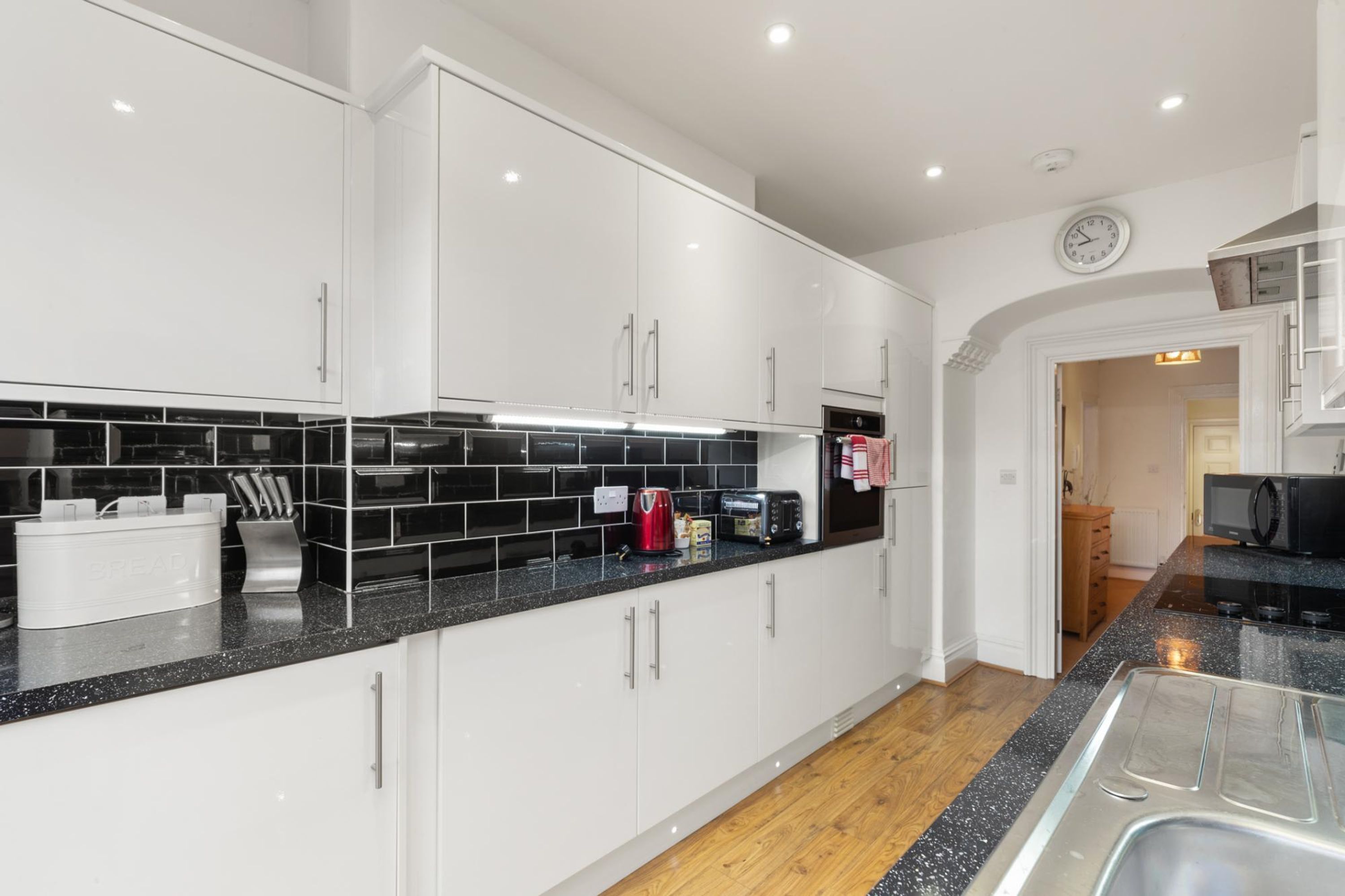 A modern kitchen with white cabinets, black countertops, and a stainless steel sink.