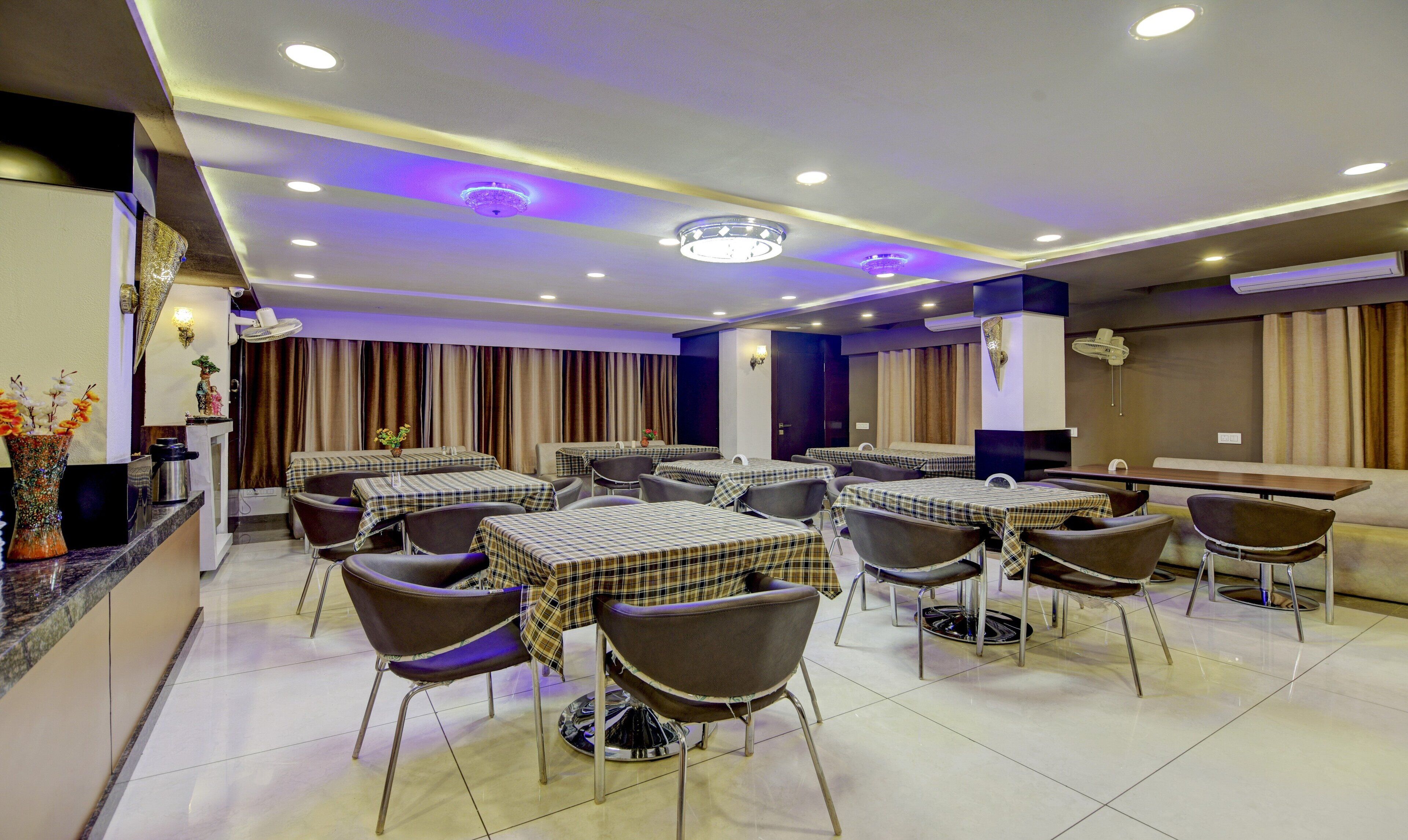 A dining area with multiple tables and chairs, a decorative vase, and a ceiling with recessed lighting.