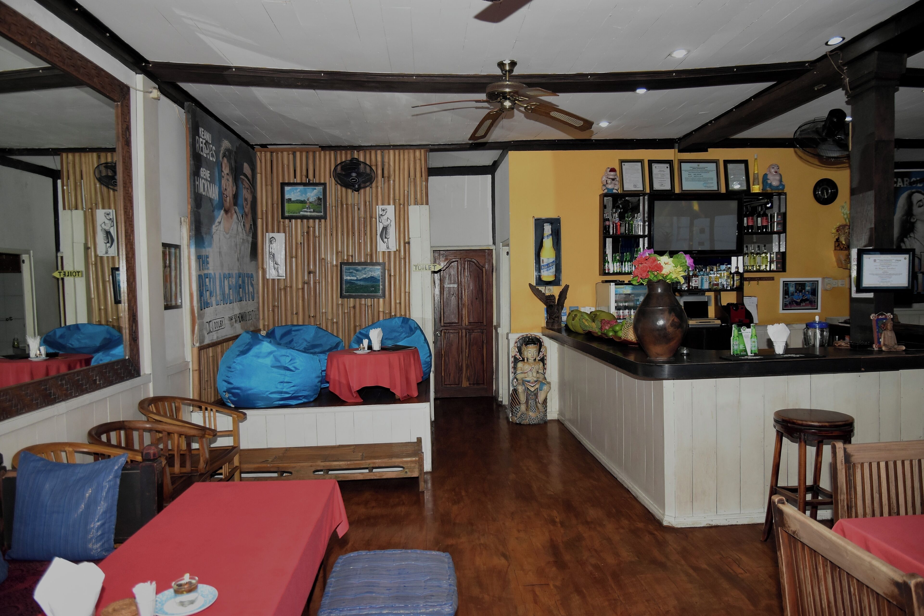 A cozy room with a wooden floor, a red sofa, a wooden dining table, and a bar area with a counter and shelves.
