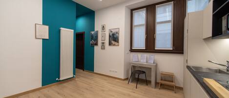 A modern kitchen with a black countertop, a window with wooden frames, and a white radiator.
