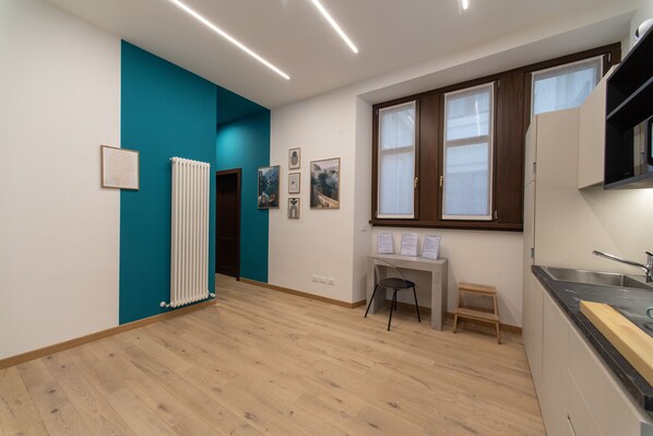 Une cuisine moderne avec un plan de travail noir, une fenêtre à cadre en bois et un radiateur blanc.