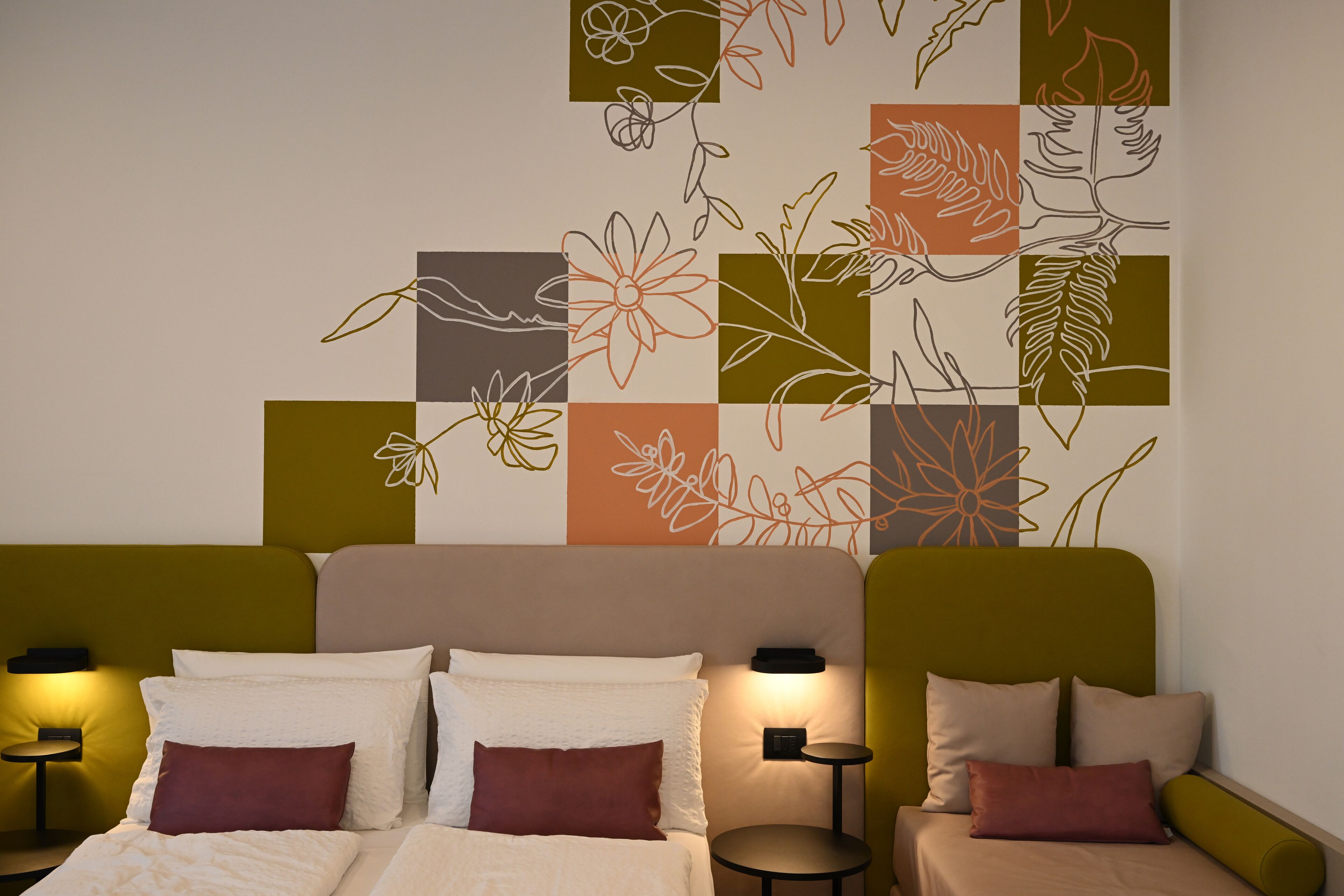 A hotel room with a bed, two bedside tables, and a wall art piece.