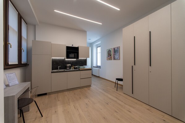 A modern kitchen with wooden flooring, built-in appliances, and a dining area with a chair. - House of Bruno - Only self check-in (Trento)