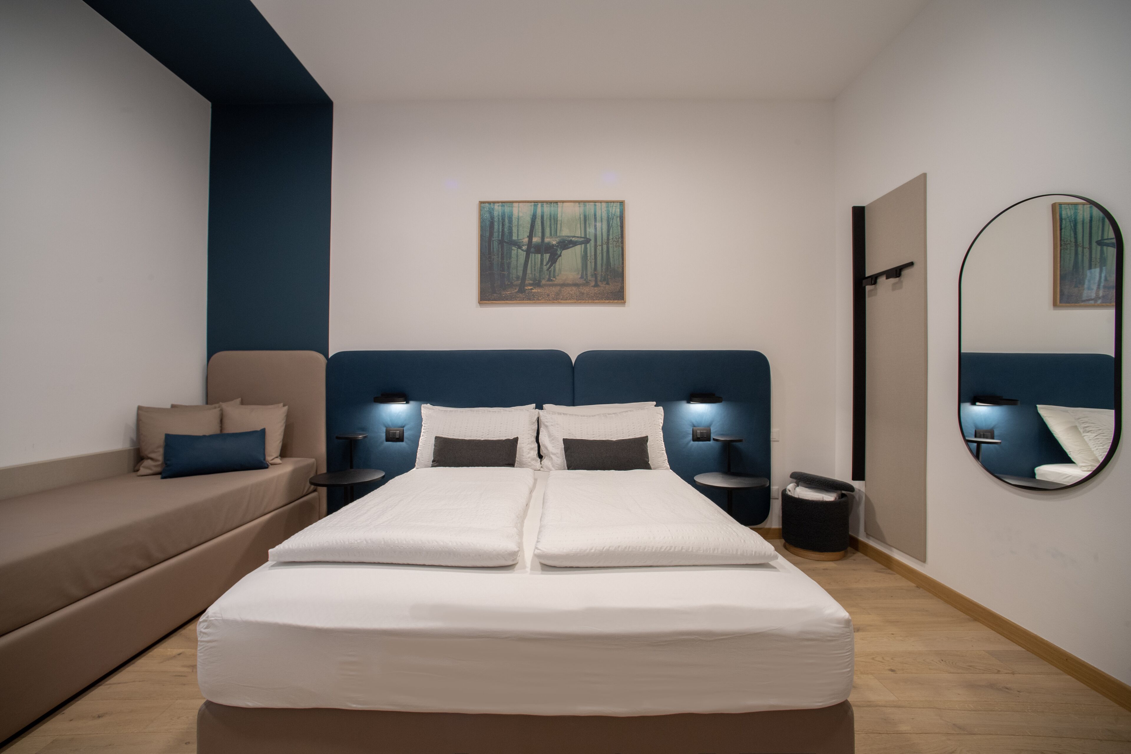 Une chambre moderne avec un grand lit, un canapé, un tableau au mur et un miroir.