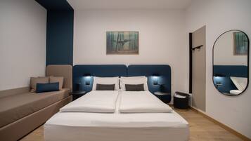 Une chambre moderne avec un grand lit, un canapé, un tableau au mur et un miroir.