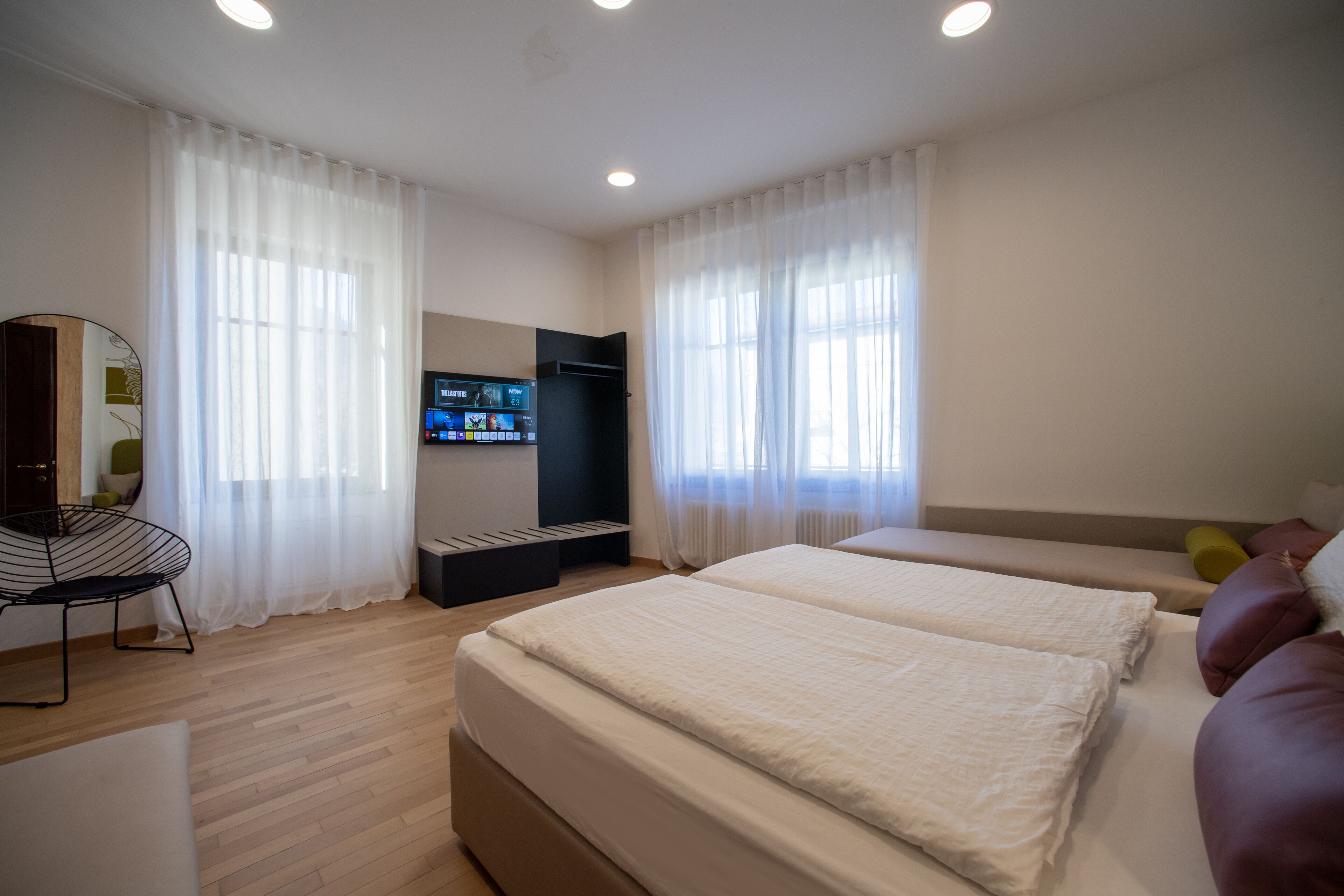 Quarto de hotel moderno com uma cama grande, televisão, escrivaninha e sofá.