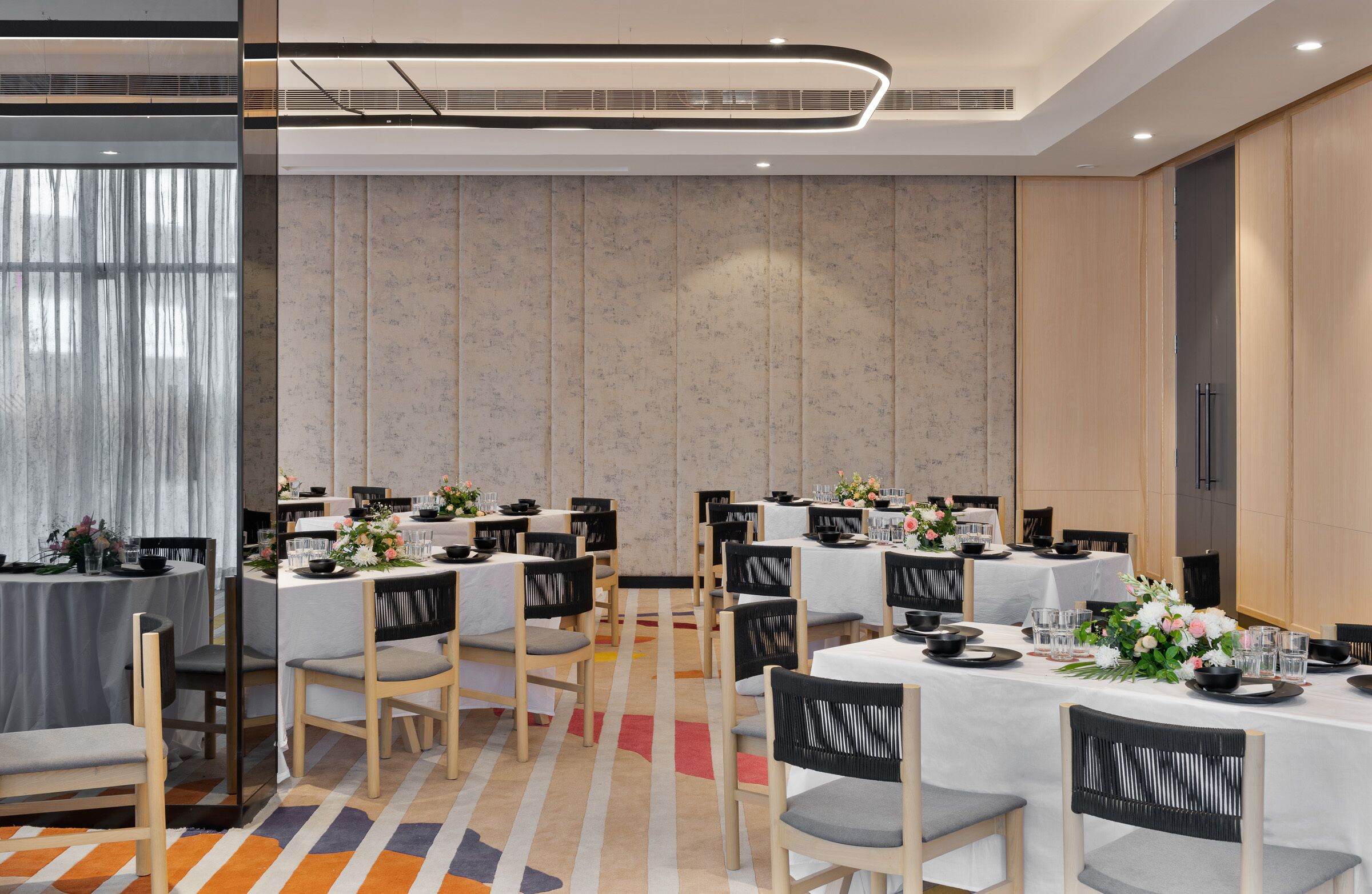 A modern dining area with multiple tables, chairs, and a decorative carpet.