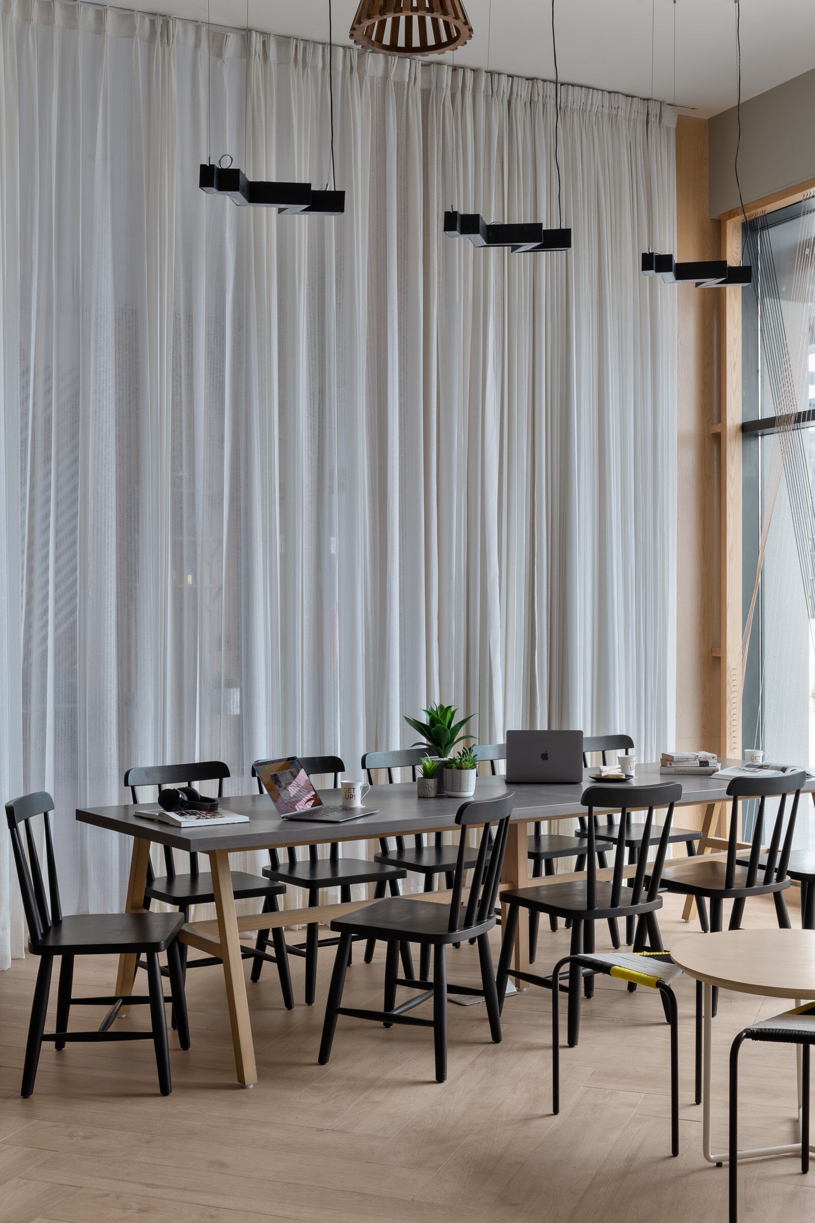 A modern meeting room with a large table, chairs, and a laptop.