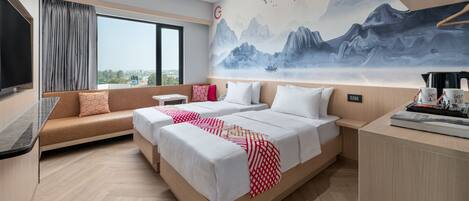 A modern hotel room with a large bed, a sofa, a TV, and a mural of mountains.