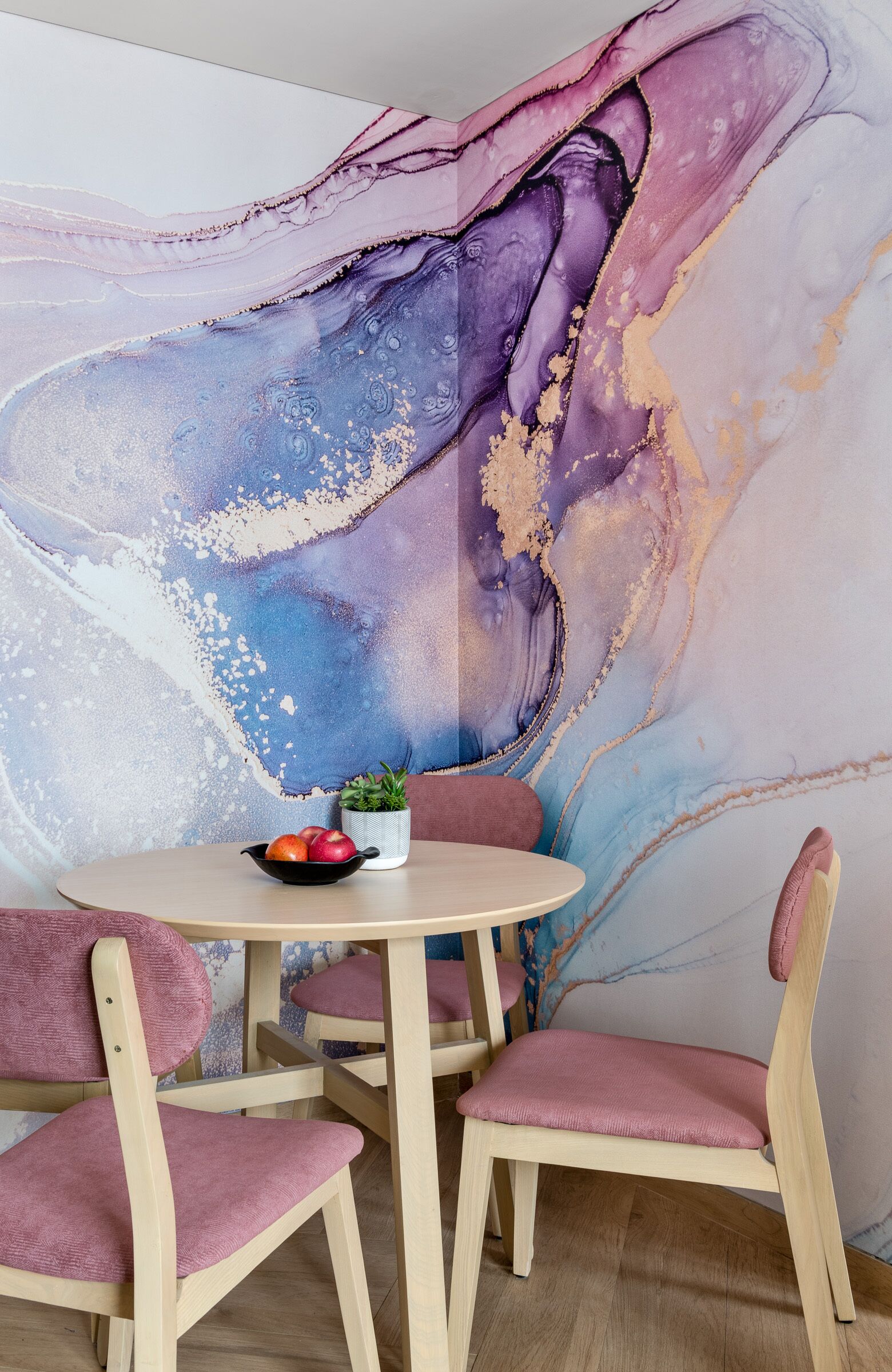 Un comedor con una mesa redonda, dos sillas y un mural en la pared.