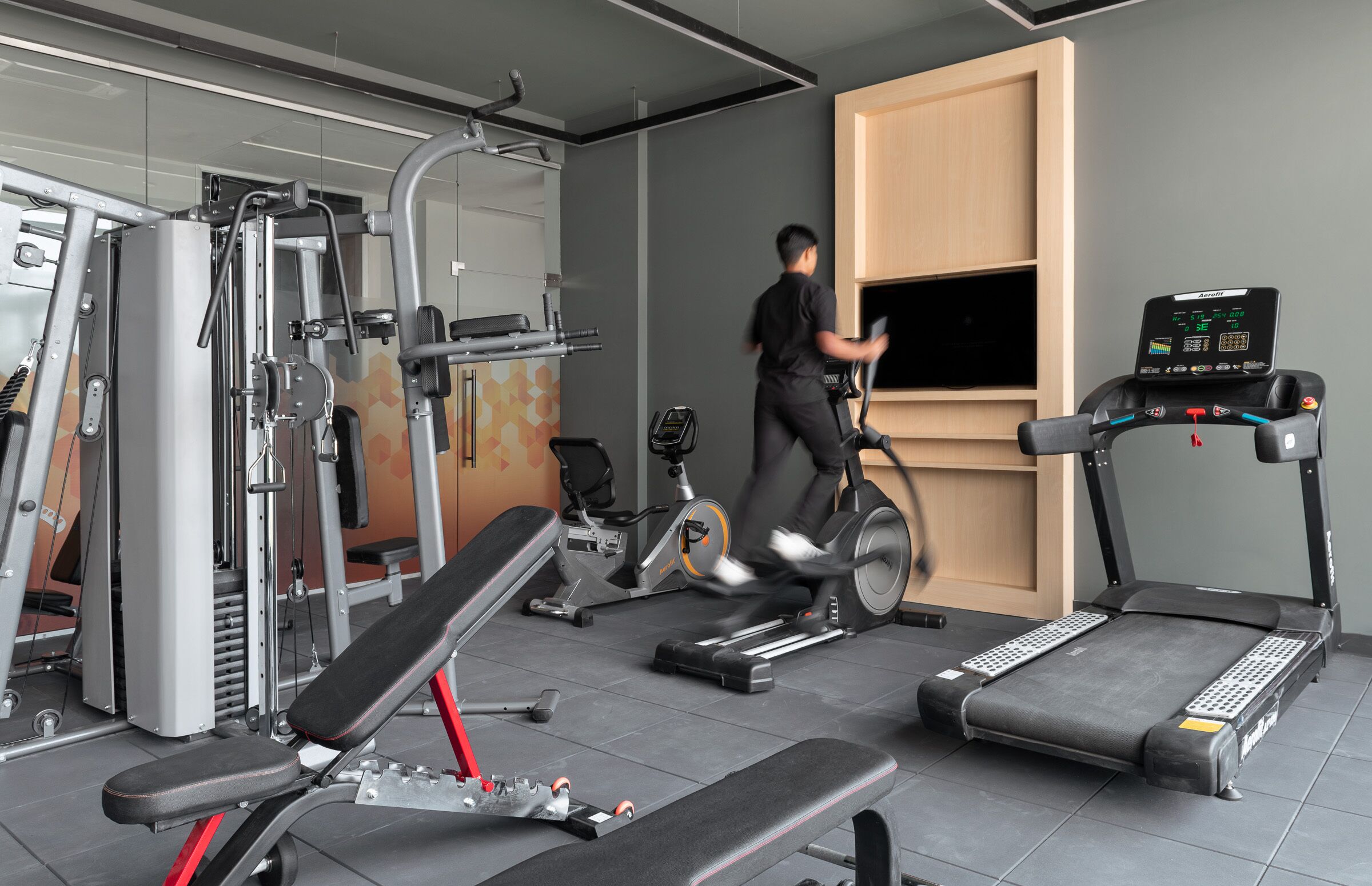 Un gimnasio con diverso equipo de ejercicio, incluyendo cintas de correr, bicicletas estáticas y máquinas de pesas.