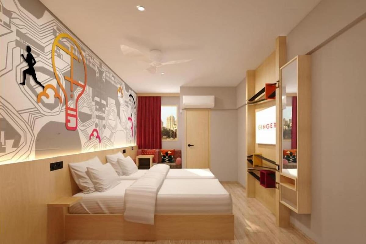 Een moderne hotelkamer met een groot bed, een bureau en een muur met abstracte kunst.