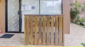 Une entrée d’immeuble avec une barrière en bois, des portes en verre et un sol carrelé.