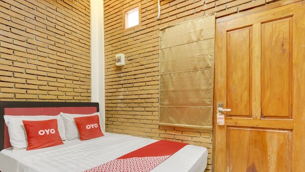 Une chambre d’hôtel avec un mur décoré d’un motif en briques, une porte en bois et un lit avec une literie rouge et blanche.