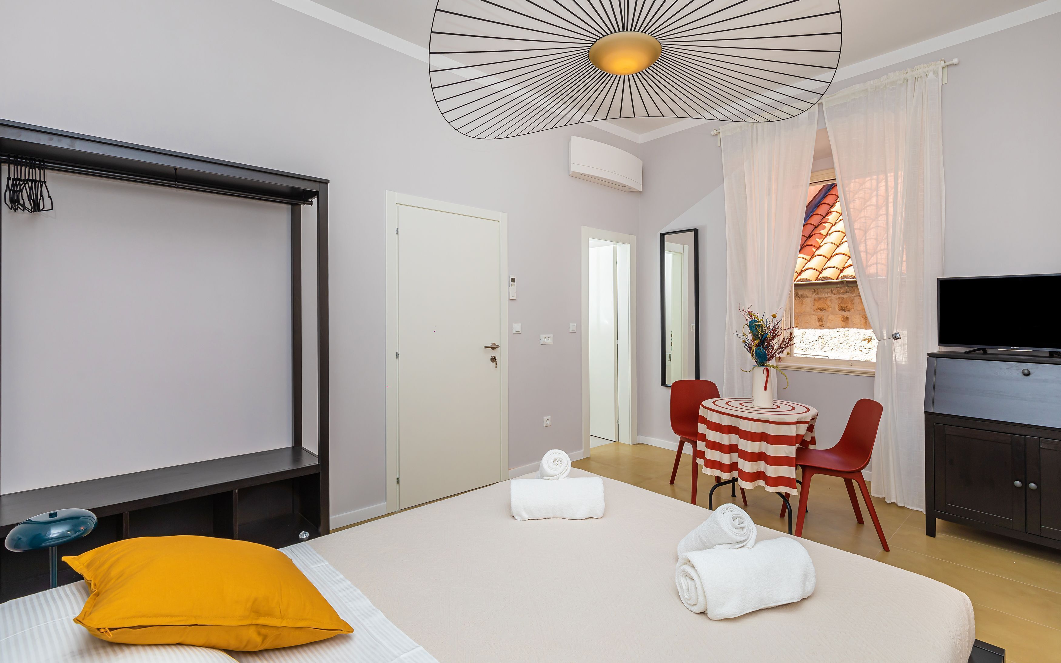 A hotel room with a bed, a desk, a TV, and a window with curtains.