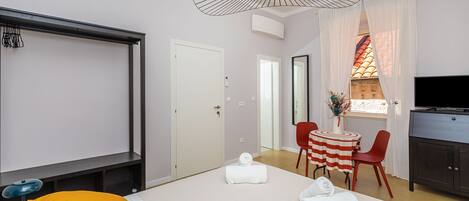 A hotel room with a bed, a desk, a TV, and a window with curtains.