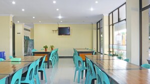 A conference room with long tables and chairs, a TV on the wall, and a view through large windows. - Collection O 91517 Hotel Gajah Mada Soe (Soe)